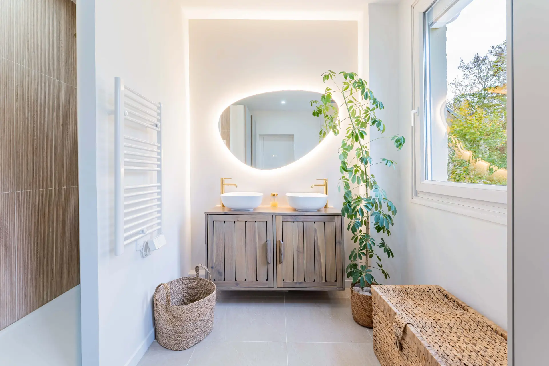 Salle de bain avec mobilier en bois, robinetterie dorée, et plantes