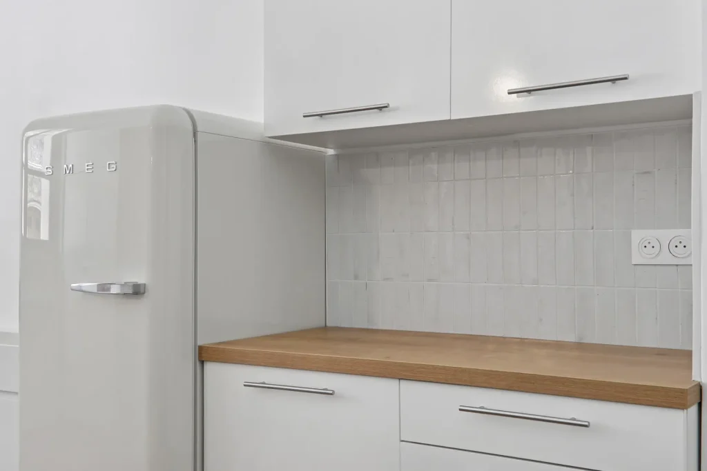 Cuisine rénovée par Sureway dans un studio à Paris 16, avec crédence blanche et frigo SMEG