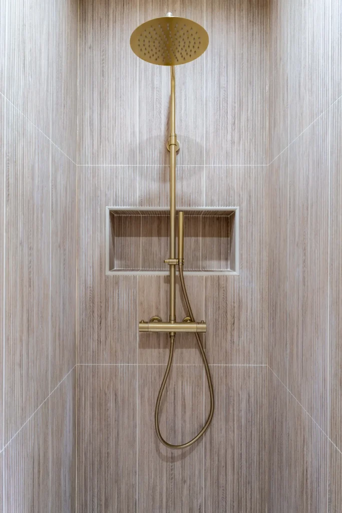 Douche avec carrelage beige et robinetterie dorée
