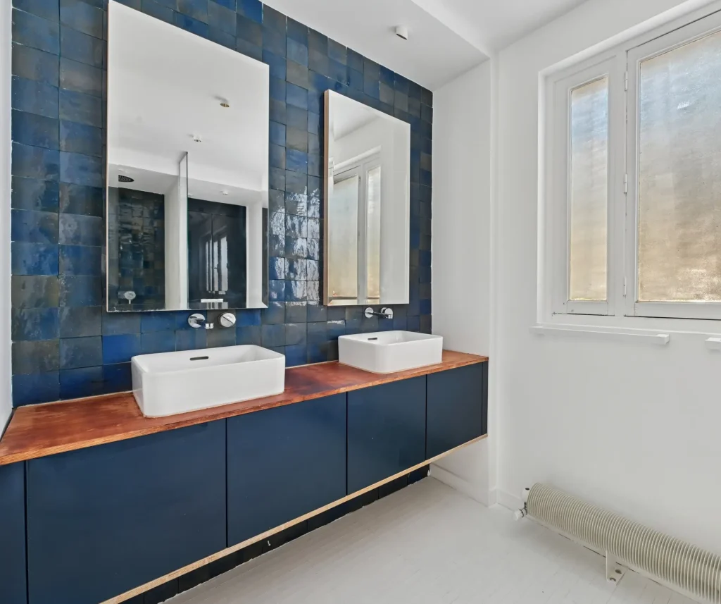 Salle de bain avec double vasque, carrelage bleu au mur et mobilier bleu