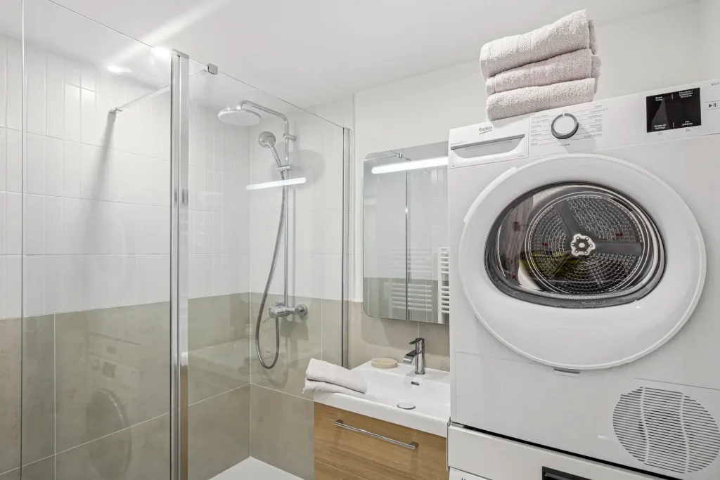 Salle de bain, avec douche, mobilier en bois et machine à laver