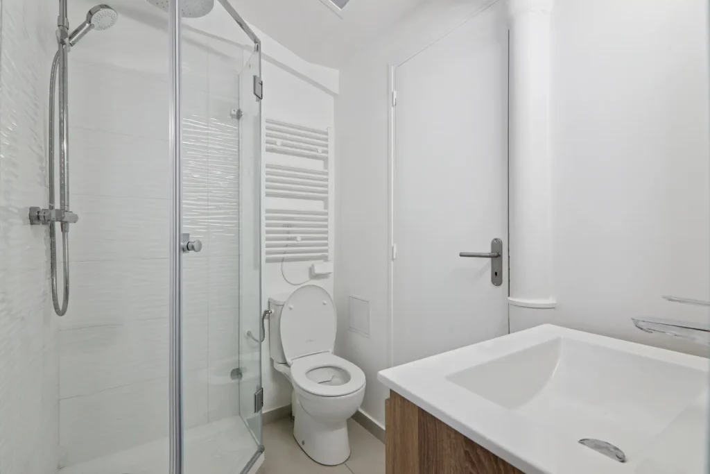 Salle de bain du studio Paris 16, avec vue sur les toilettes et la douche en angle, entièrement rénovée par Sureway