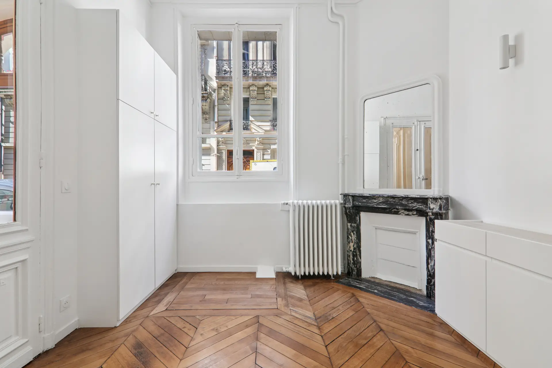 Studio Paris avec cheminée en marbre, fenêtres donnant sur la rue, et parquet en chevron